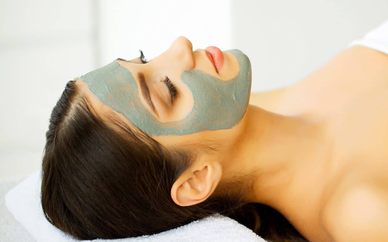 Beautiful Woman With Cosmetic Mask on Face. Girl Gets Treatment in Spa Salon against white Background. Homemade mask for face. spa treatments.